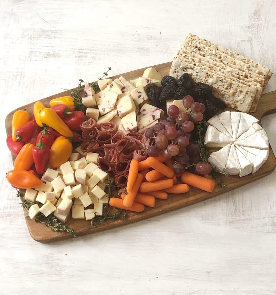 charcuterie board with cheese, crackers, grapes, cured meats, carrots and dried figs